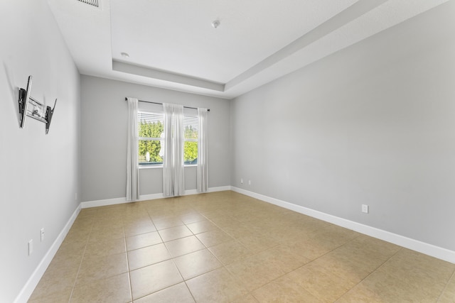 tiled empty room with a raised ceiling