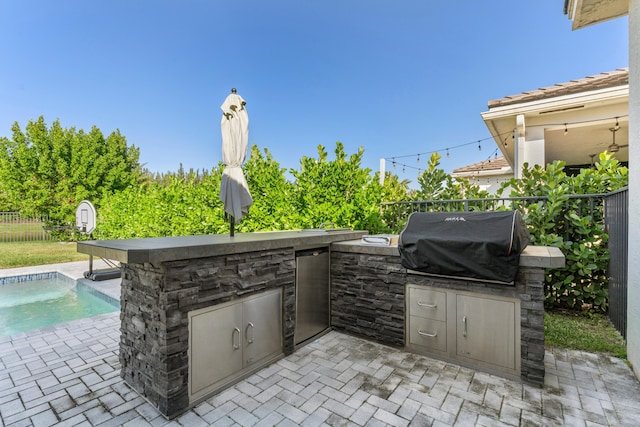 view of patio / terrace with a fenced in pool, a grill, and an outdoor kitchen