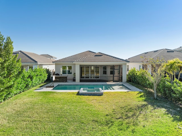 rear view of property with a pool with hot tub, exterior kitchen, a patio, and a yard