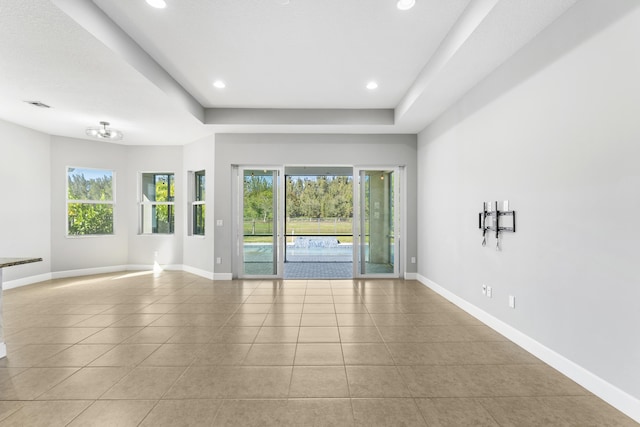 unfurnished room with a raised ceiling and light tile patterned floors