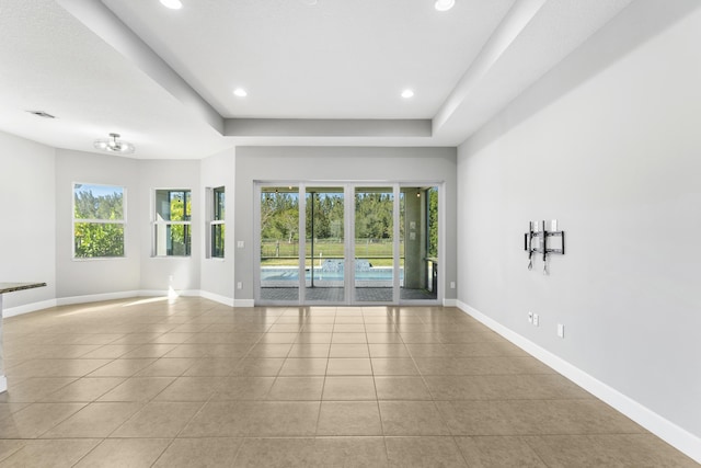 tiled spare room with a raised ceiling