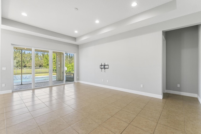 tiled empty room with a tray ceiling