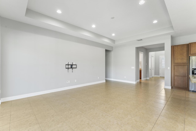 unfurnished room with a tray ceiling and light tile patterned floors