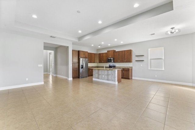 kitchen featuring a tray ceiling, a kitchen island, light tile patterned floors, and appliances with stainless steel finishes