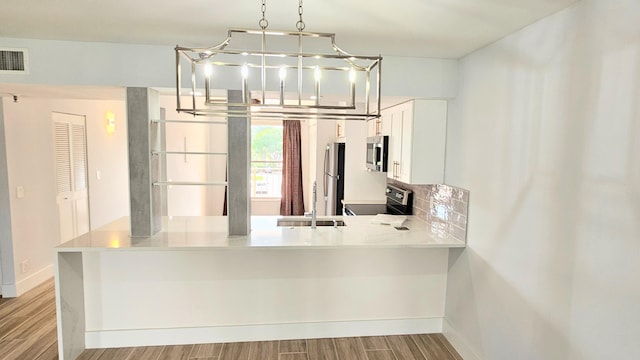 kitchen with kitchen peninsula, appliances with stainless steel finishes, and light hardwood / wood-style flooring