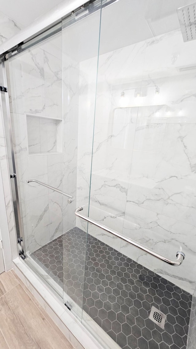 bathroom with wood-type flooring and a shower with door