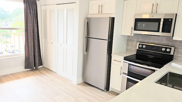 kitchen featuring light wood-type flooring, stainless steel appliances, white cabinetry, and tasteful backsplash