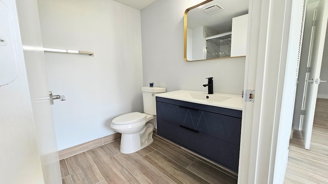 bathroom with hardwood / wood-style floors, vanity, and toilet