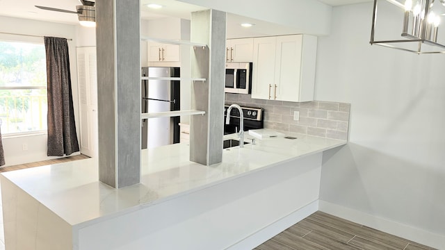 kitchen with light hardwood / wood-style flooring, decorative backsplash, light stone countertops, appliances with stainless steel finishes, and white cabinetry