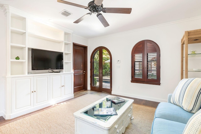 living room with french doors, crown molding, light hardwood / wood-style flooring, ceiling fan, and built in features