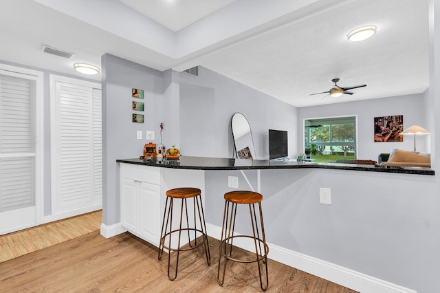 bar featuring white cabinetry, ceiling fan, and light hardwood / wood-style floors