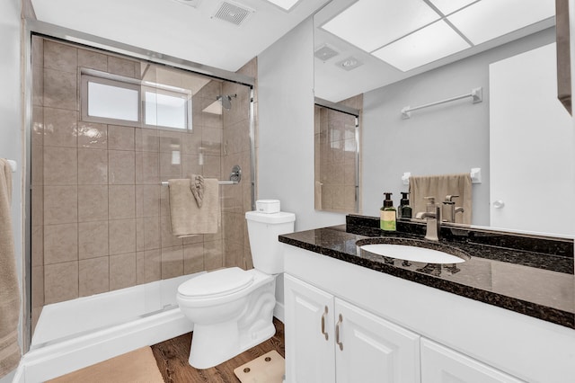 bathroom featuring a shower with door, vanity, wood-type flooring, and toilet