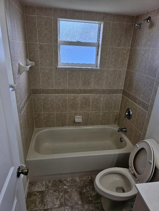 bathroom featuring tiled shower / bath combo and toilet