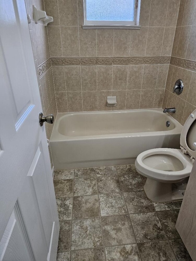 bathroom with toilet and tiled shower / bath