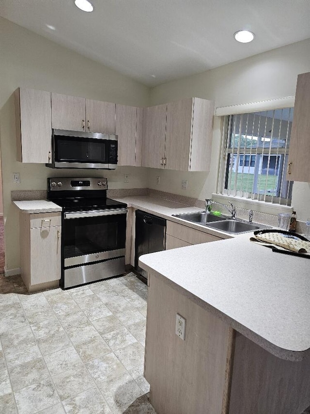 kitchen with light brown cabinets, sink, vaulted ceiling, kitchen peninsula, and stainless steel appliances