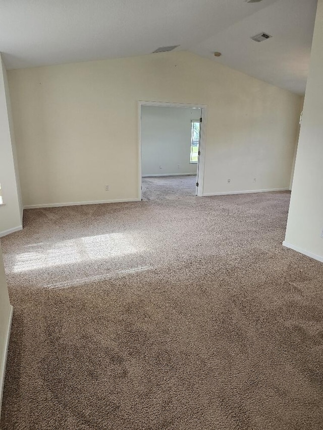 carpeted empty room with lofted ceiling