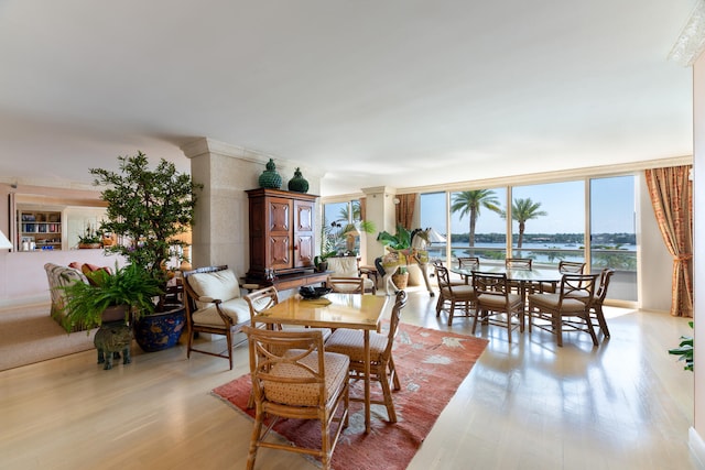 dining area with light wood-type flooring and a water view