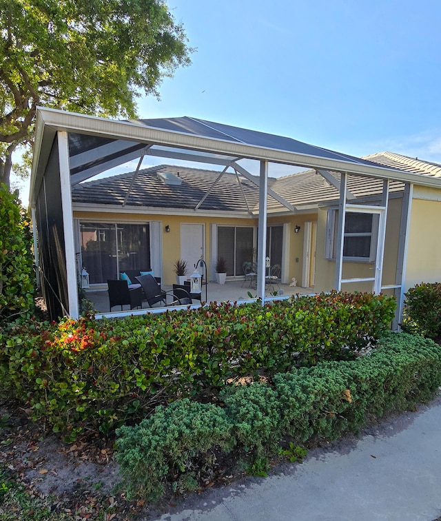 back of house with glass enclosure and a patio