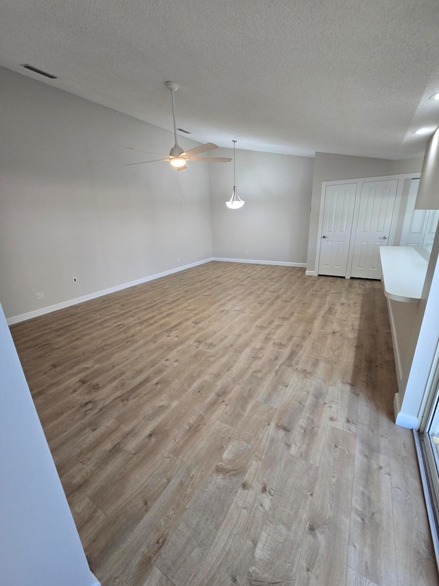 unfurnished room featuring a textured ceiling, light hardwood / wood-style floors, and vaulted ceiling