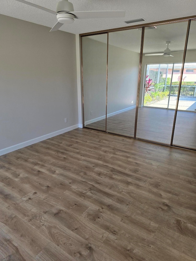 unfurnished bedroom with a textured ceiling, a closet, hardwood / wood-style flooring, and ceiling fan