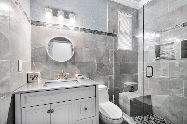 bathroom featuring walk in shower, vanity, toilet, and tile walls