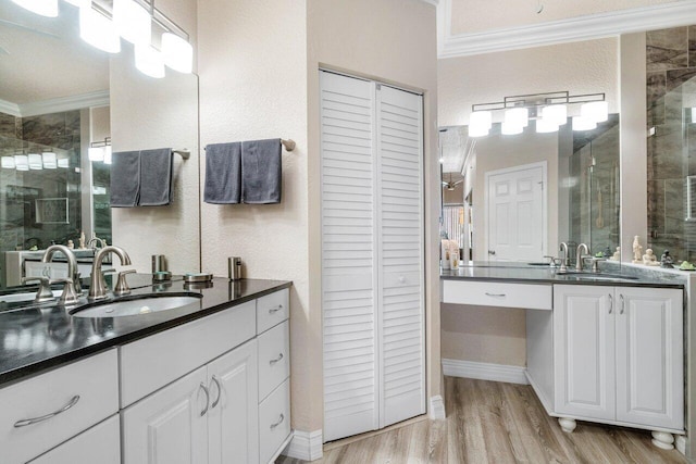 bathroom with a shower with door, crown molding, hardwood / wood-style flooring, and vanity