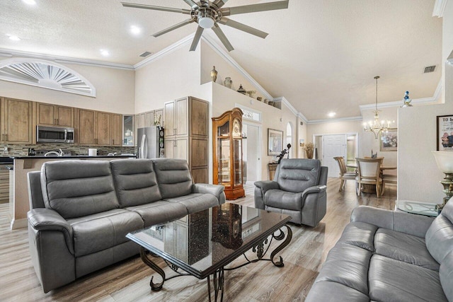 living room with high vaulted ceiling, ornamental molding, a textured ceiling, ceiling fan with notable chandelier, and light wood-type flooring