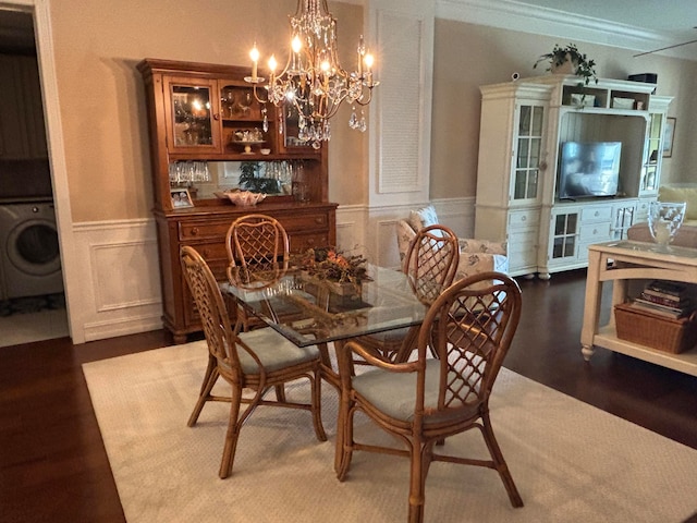 dining area with washer / clothes dryer, crown molding, dark hardwood / wood-style flooring, and a chandelier