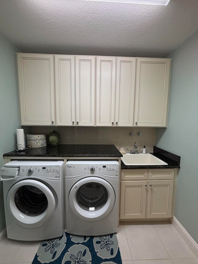 clothes washing area with washing machine and clothes dryer, sink, cabinets, and a textured ceiling