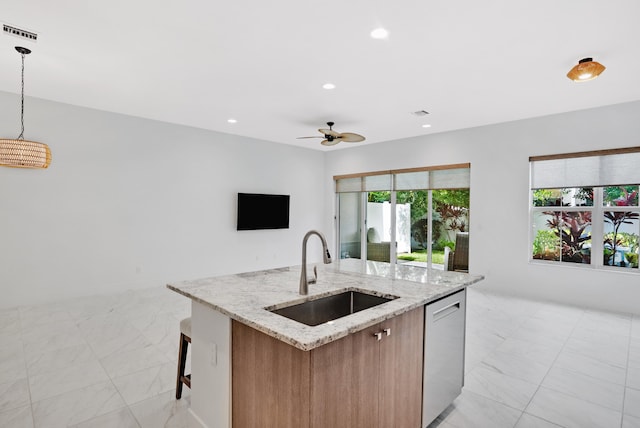 kitchen with light stone countertops, dishwasher, sink, hanging light fixtures, and a center island with sink