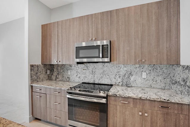 kitchen featuring tasteful backsplash, light stone counters, and appliances with stainless steel finishes