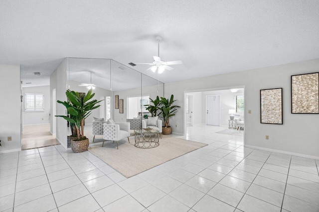 interior space featuring ceiling fan, light tile patterned floors, a textured ceiling, and vaulted ceiling