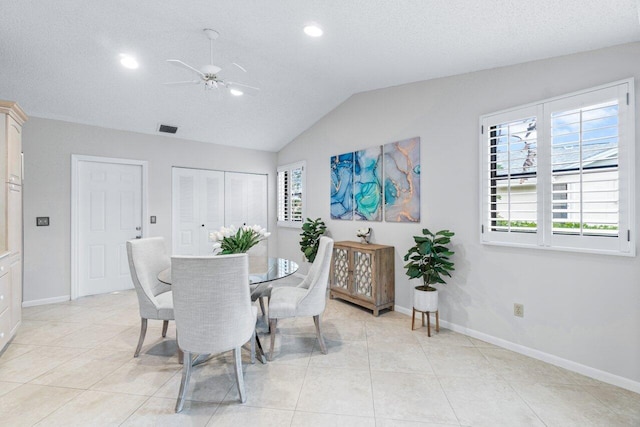 tiled dining space with a textured ceiling, vaulted ceiling, and ceiling fan