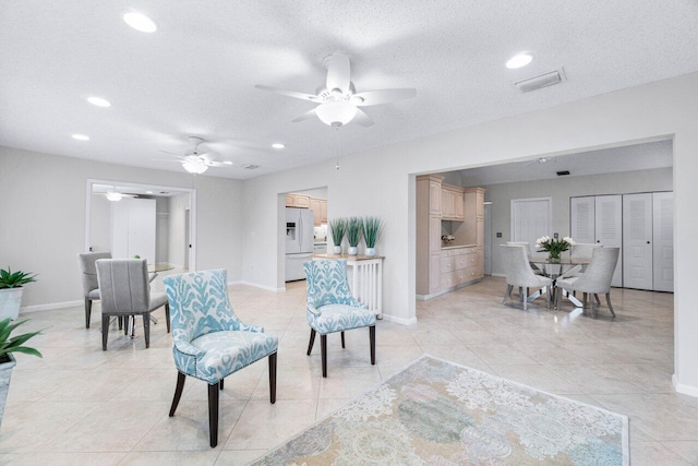 sitting room featuring ceiling fan, light tile patterned floors, and a textured ceiling