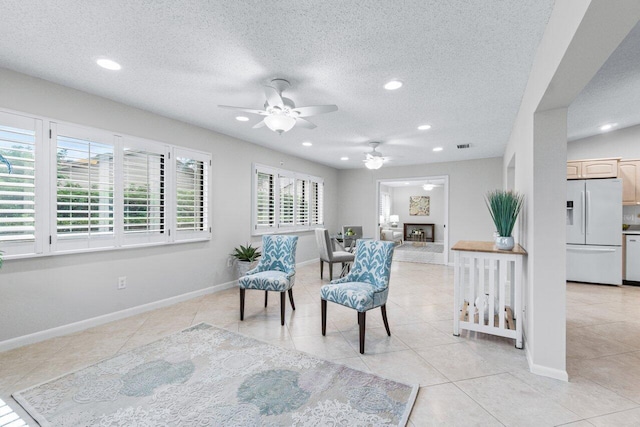 living area with ceiling fan, light tile patterned flooring, and a textured ceiling