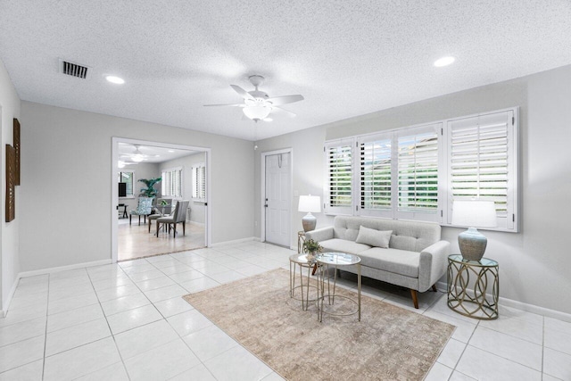 tiled living room with ceiling fan and a textured ceiling