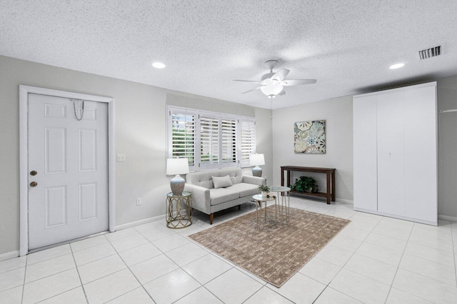 living room featuring ceiling fan, light tile patterned floors, and a textured ceiling