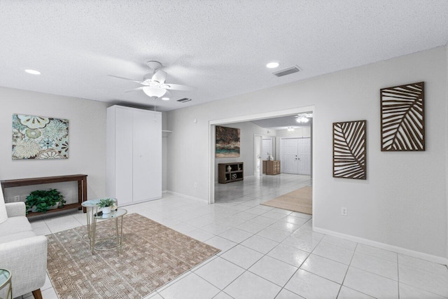 living room featuring ceiling fan, light tile patterned floors, and a textured ceiling