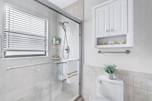 bathroom featuring an enclosed shower, toilet, and tile walls