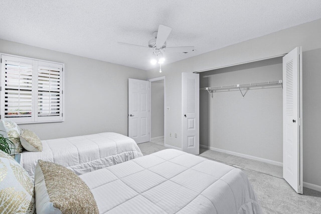 bedroom with ceiling fan, a textured ceiling, light carpet, and a closet