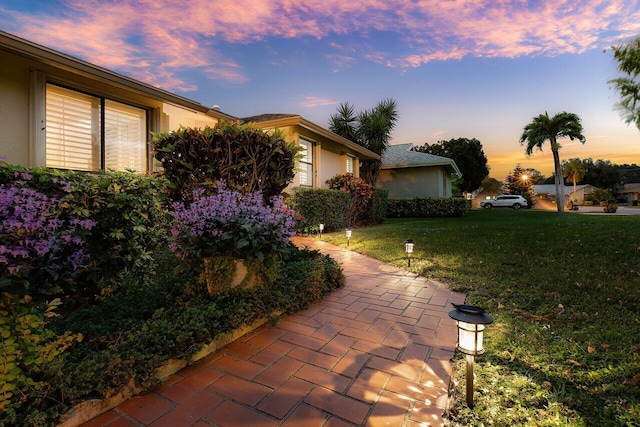 property exterior at dusk with a lawn and a patio area