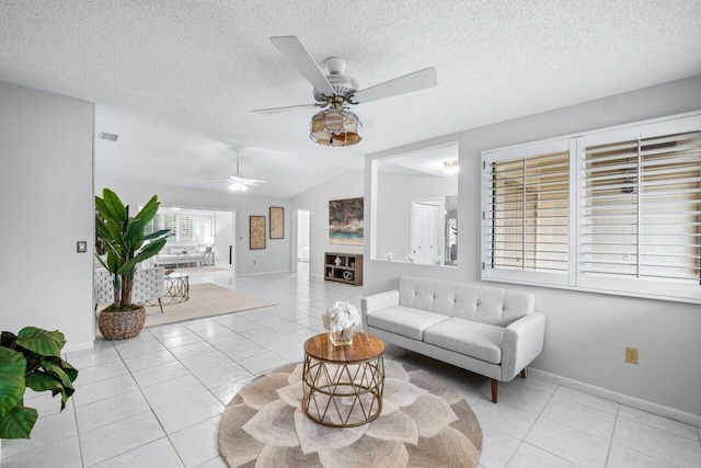 tiled living room with a textured ceiling, vaulted ceiling, and ceiling fan