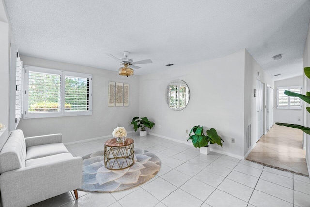 living room featuring ceiling fan, light tile patterned floors, and a textured ceiling