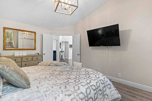 bedroom with a textured ceiling, a chandelier, lofted ceiling, and hardwood / wood-style flooring