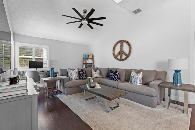 living room featuring ceiling fan, dark hardwood / wood-style flooring, lofted ceiling, and a textured ceiling