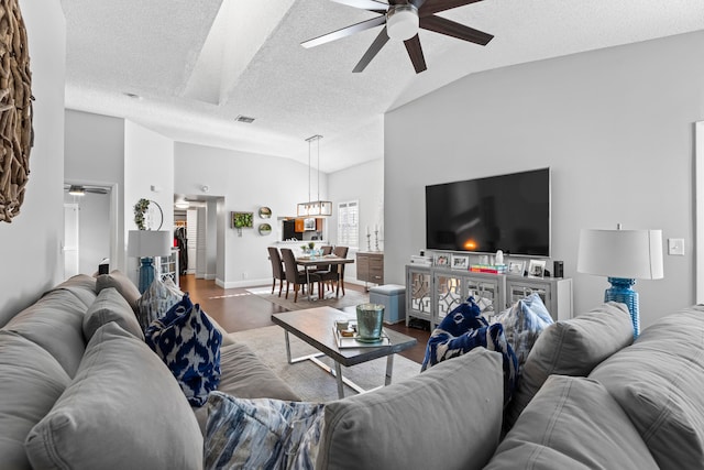 living room with wood-type flooring, a textured ceiling, vaulted ceiling, and ceiling fan