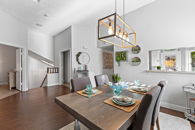 dining area with dark hardwood / wood-style flooring, a towering ceiling, and a textured ceiling