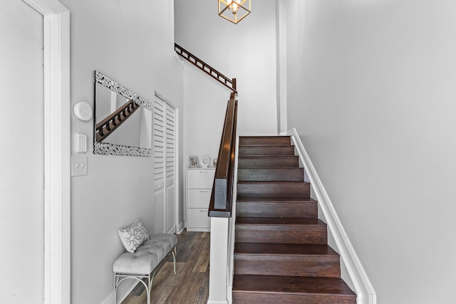 stairway with hardwood / wood-style floors and a notable chandelier