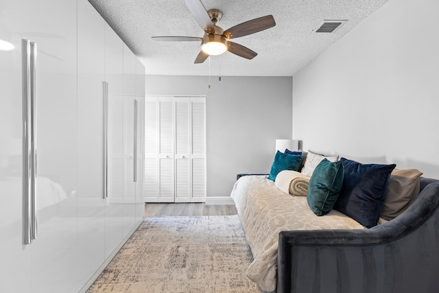 bedroom featuring light wood-type flooring, a textured ceiling, and ceiling fan