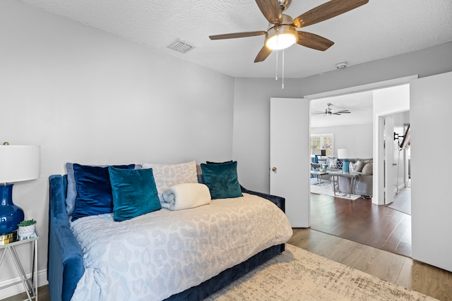 bedroom featuring hardwood / wood-style flooring, ceiling fan, and a textured ceiling